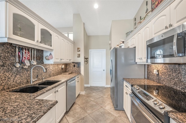 kitchen featuring appliances with stainless steel finishes, sink, white cabinets, dark stone counters, and light tile patterned floors