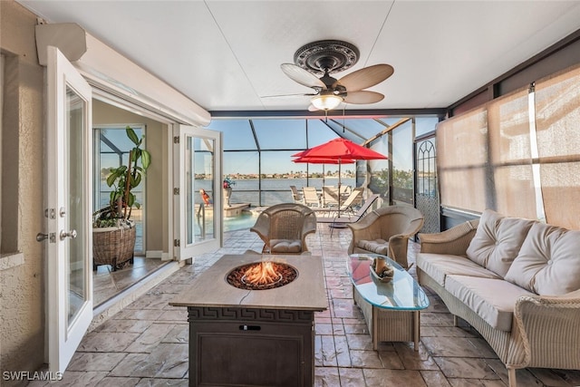 sunroom featuring plenty of natural light, ceiling fan, and a water view