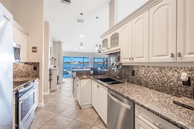 kitchen with sink, dark stone countertops, stainless steel appliances, tasteful backsplash, and white cabinets