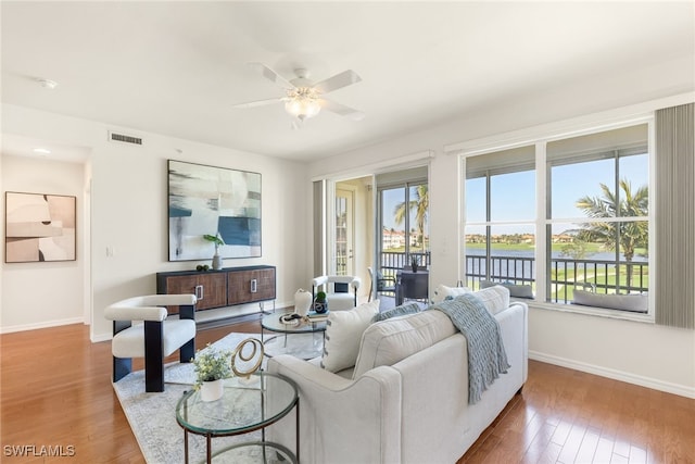 living room with hardwood / wood-style flooring, ceiling fan, and a water view