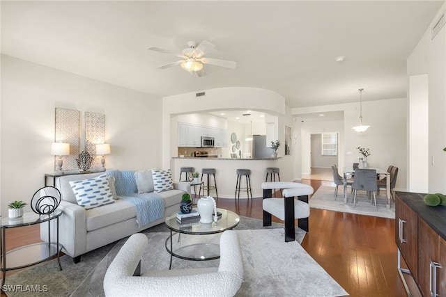 living room with dark hardwood / wood-style flooring and ceiling fan