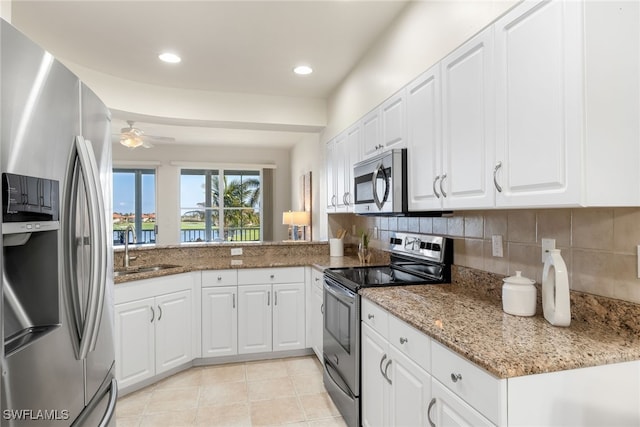 kitchen with light stone counters, sink, white cabinets, and appliances with stainless steel finishes