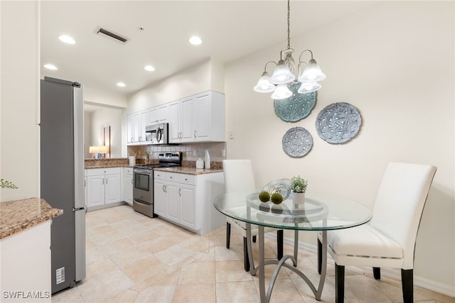 kitchen featuring hanging light fixtures, decorative backsplash, white cabinets, and appliances with stainless steel finishes