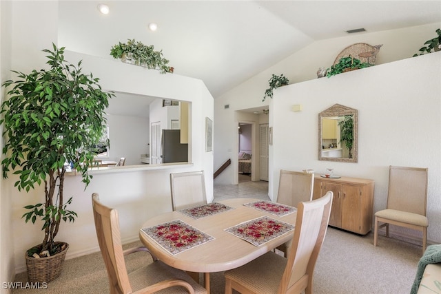 carpeted dining room with vaulted ceiling