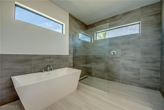 bathroom featuring independent shower and bath and tile walls