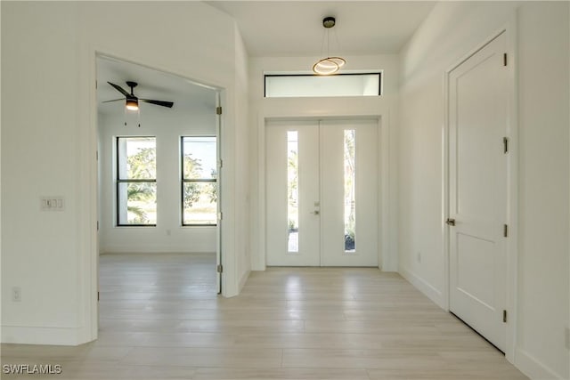 foyer entrance with plenty of natural light, light hardwood / wood-style floors, french doors, and ceiling fan