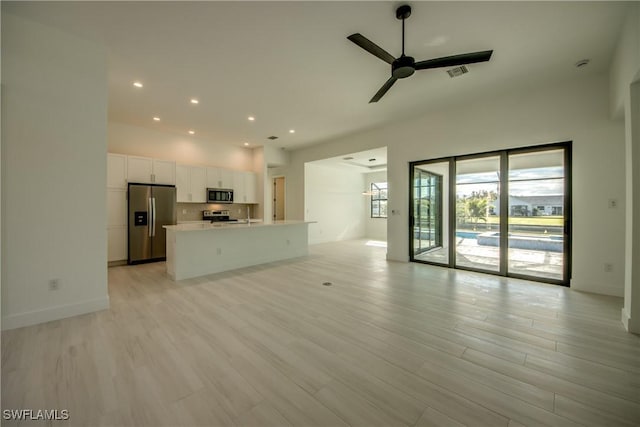 unfurnished living room with ceiling fan and light wood-type flooring