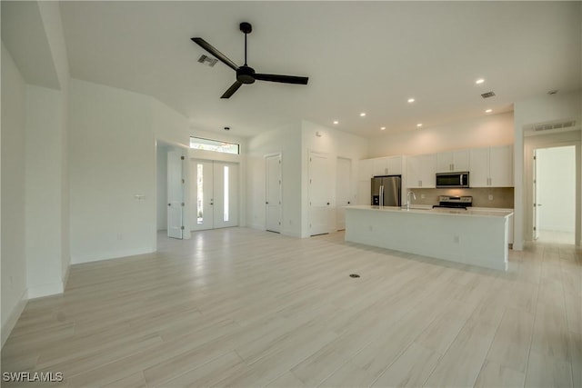 unfurnished living room featuring sink, ceiling fan, and light wood-type flooring