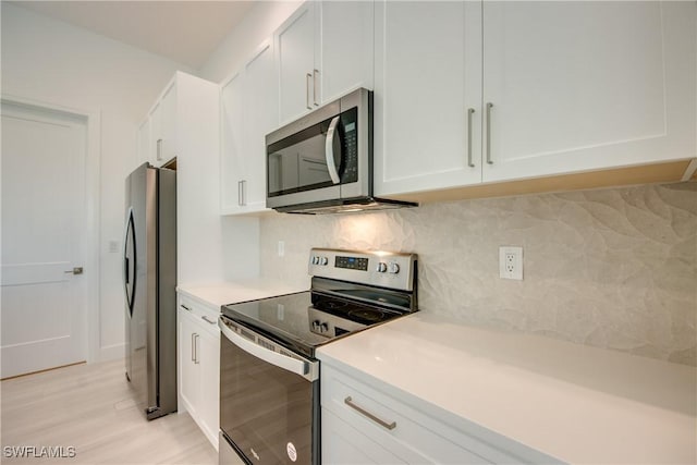 kitchen featuring white cabinetry, appliances with stainless steel finishes, light hardwood / wood-style flooring, and decorative backsplash