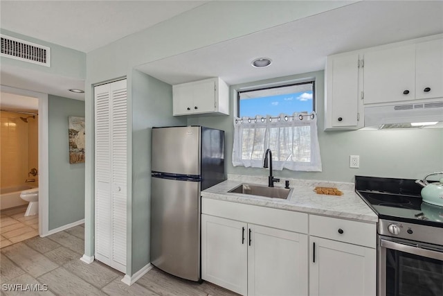 kitchen with white cabinetry, appliances with stainless steel finishes, sink, and light hardwood / wood-style floors