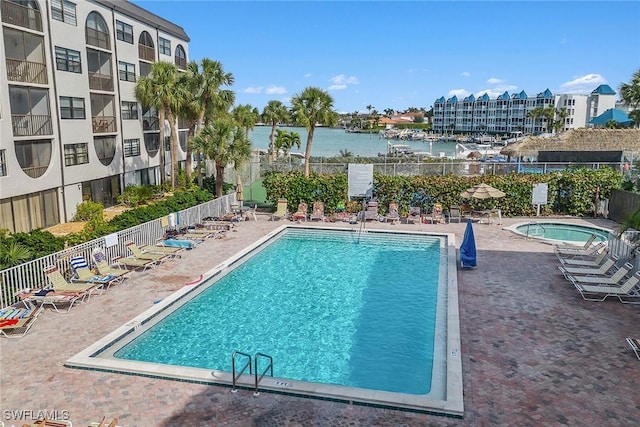 view of pool featuring a water view, a hot tub, and a patio area