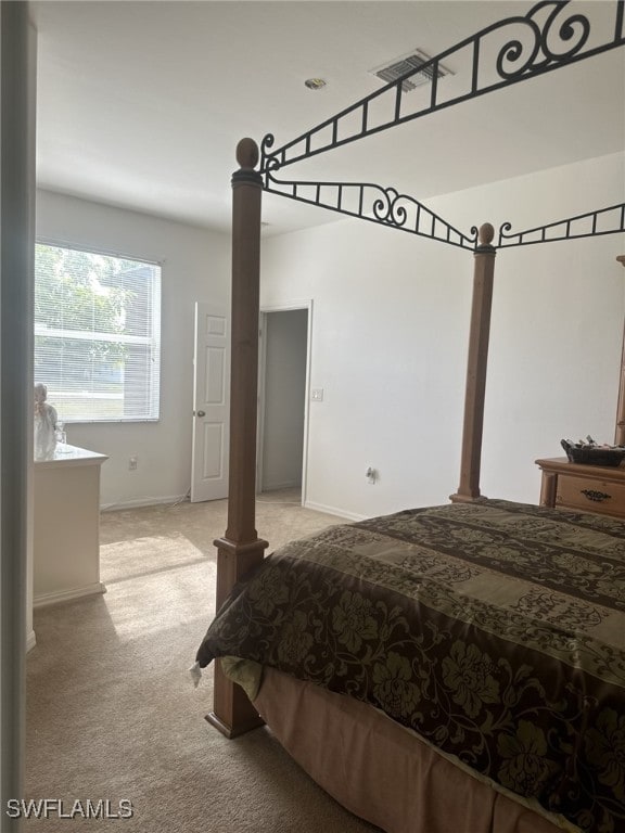 bedroom with ornate columns and light colored carpet