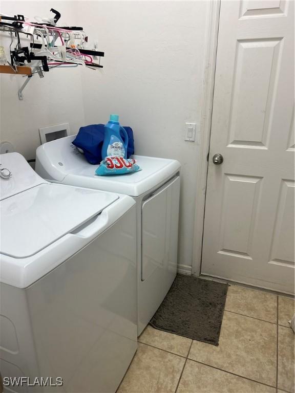 laundry area with light tile patterned floors and washer and clothes dryer