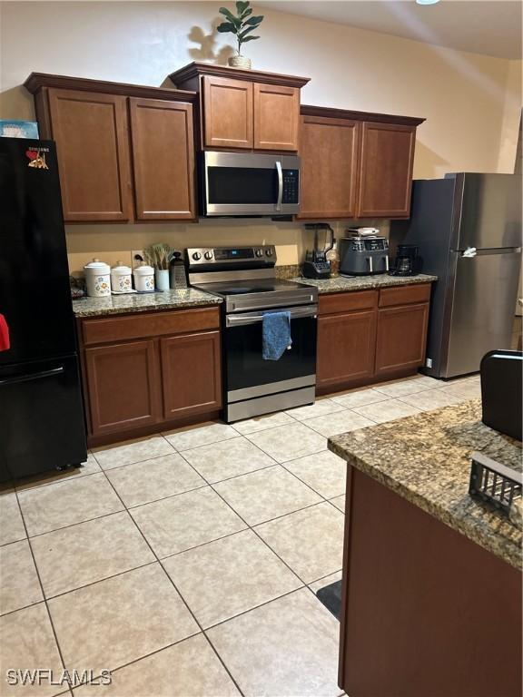 kitchen featuring stainless steel appliances, light tile patterned flooring, and light stone countertops