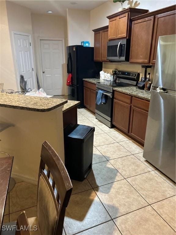 kitchen featuring light stone counters, stainless steel appliances, and light tile patterned floors