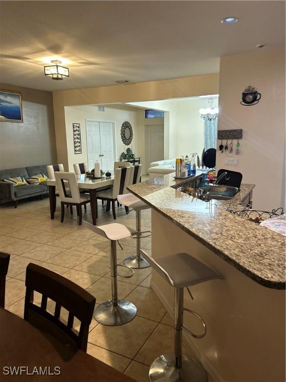 kitchen with light tile patterned flooring, light stone counters, and a breakfast bar area