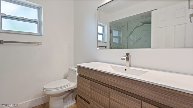 bathroom featuring vanity, a healthy amount of sunlight, an enclosed shower, and toilet