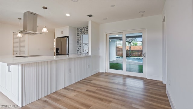 kitchen with stainless steel fridge with ice dispenser, hanging light fixtures, kitchen peninsula, hardwood / wood-style flooring, and white cabinets