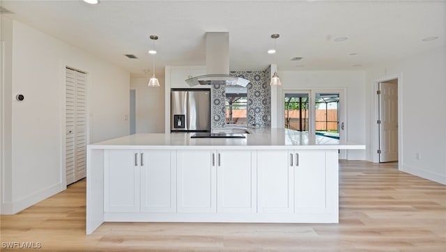 kitchen featuring stainless steel refrigerator with ice dispenser, white cabinetry, hanging light fixtures, light hardwood / wood-style flooring, and island exhaust hood