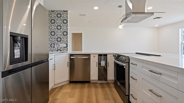 kitchen featuring tasteful backsplash, white cabinetry, hanging light fixtures, light hardwood / wood-style floors, and stainless steel appliances