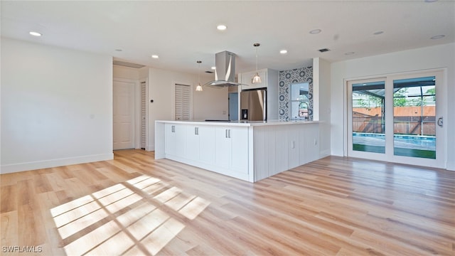 kitchen with decorative light fixtures, stainless steel fridge with ice dispenser, kitchen peninsula, island exhaust hood, and white cabinets