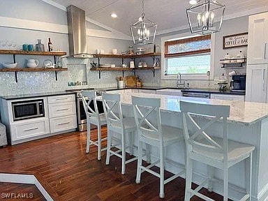 kitchen featuring stainless steel appliances, extractor fan, a breakfast bar area, and white cabinets