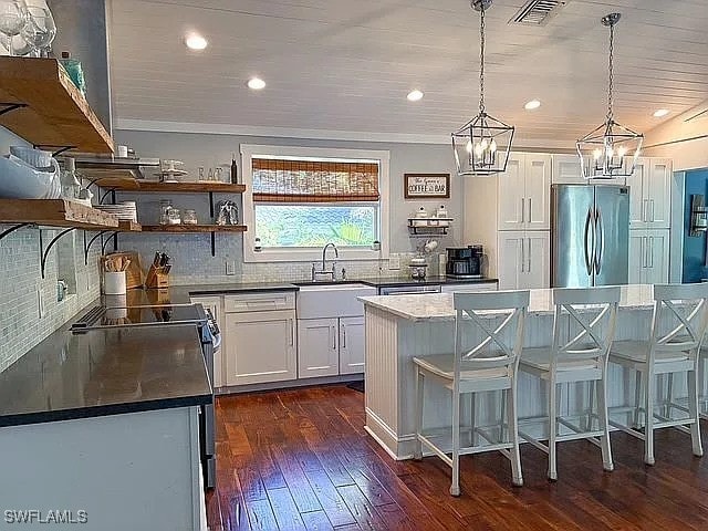 kitchen featuring appliances with stainless steel finishes, a kitchen island, hanging light fixtures, and white cabinets