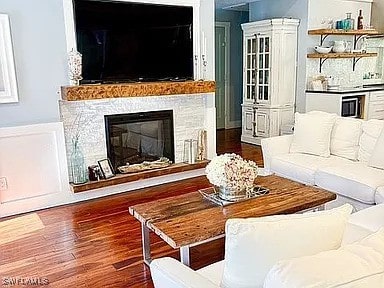 living room with a stone fireplace and dark hardwood / wood-style floors