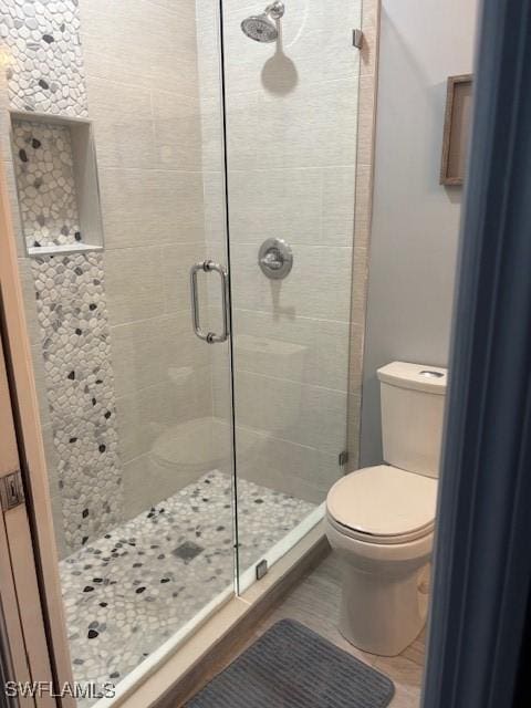 bathroom with a shower with door and toilet