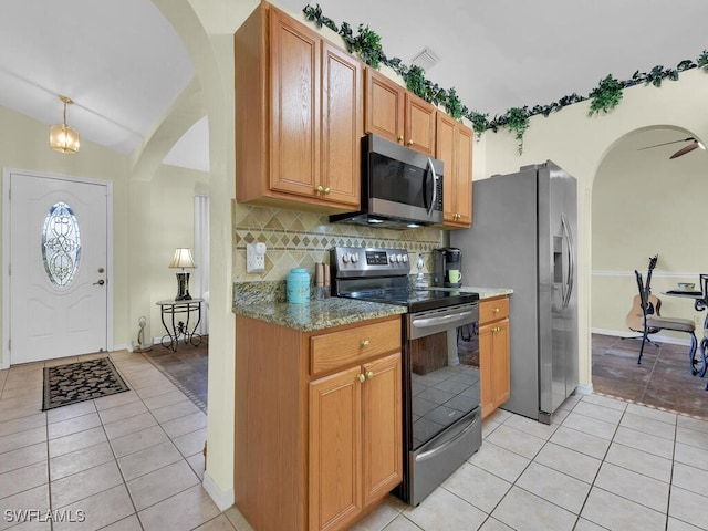 kitchen featuring light stone countertops, light tile patterned flooring, appliances with stainless steel finishes, and backsplash