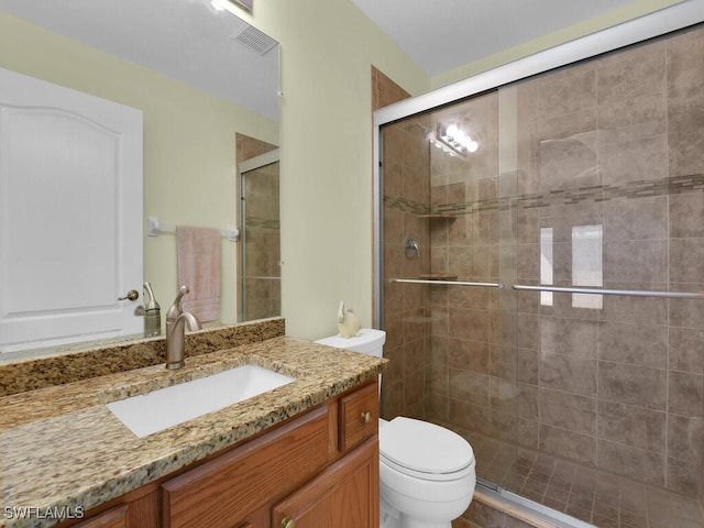 bathroom featuring vanity, a shower with door, and toilet