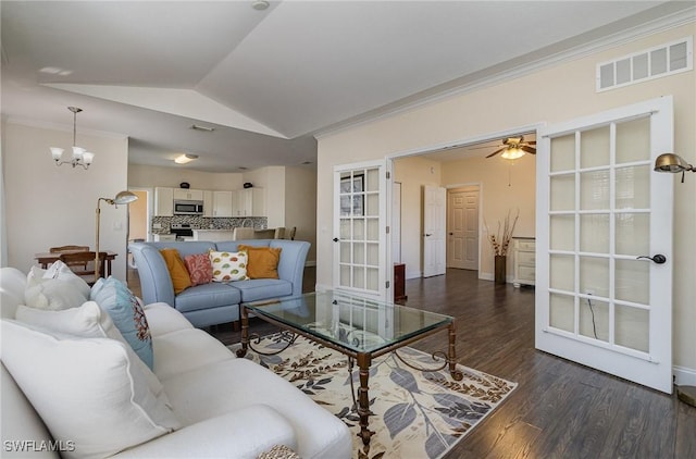 living room featuring dark hardwood / wood-style floors, ceiling fan with notable chandelier, lofted ceiling, crown molding, and french doors