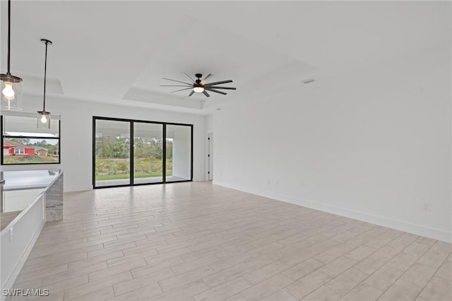 unfurnished living room featuring a tray ceiling and ceiling fan