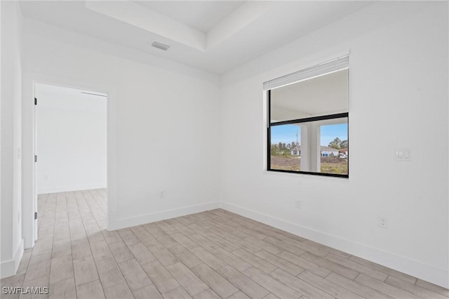 empty room featuring light hardwood / wood-style flooring and a raised ceiling