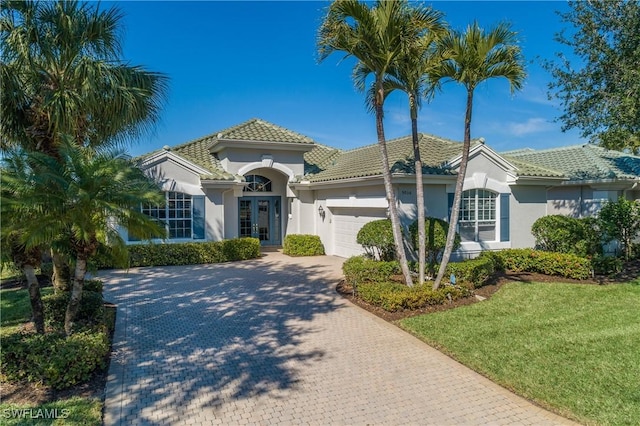 mediterranean / spanish home with a garage and a front lawn