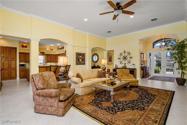 living room featuring light tile patterned floors, crown molding, ceiling fan, a towering ceiling, and decorative columns