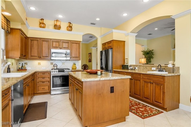 kitchen with light stone counters, stainless steel appliances, sink, and a kitchen island