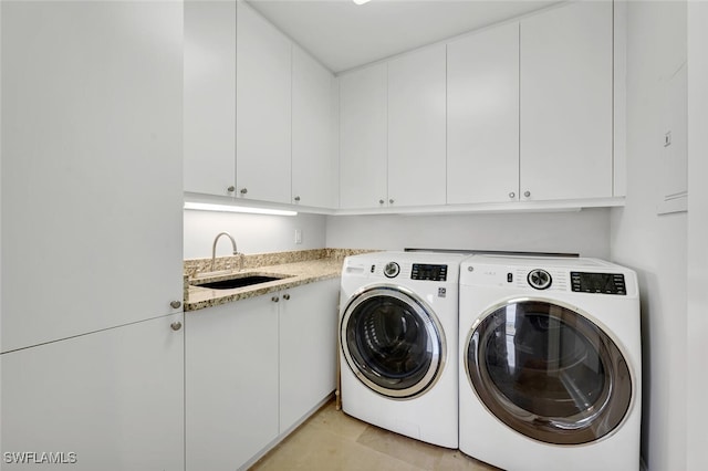 laundry room with cabinet space, washing machine and dryer, and a sink