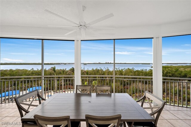 sunroom featuring a water view, plenty of natural light, and a ceiling fan