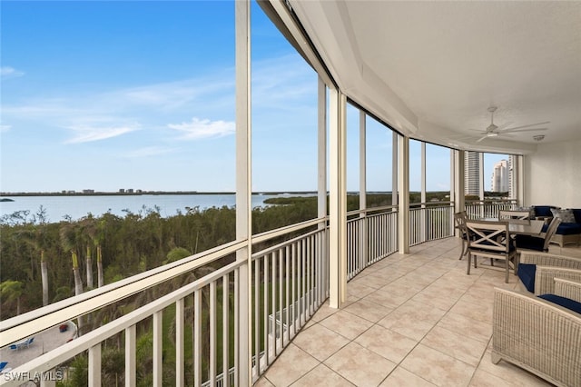 sunroom with a ceiling fan and a water view