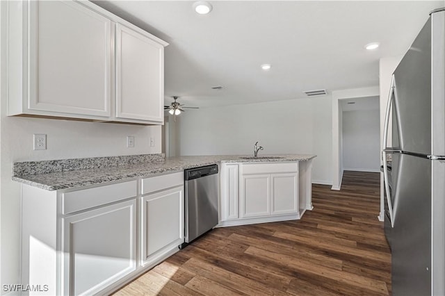 kitchen featuring sink, white cabinetry, stainless steel appliances, light stone countertops, and kitchen peninsula