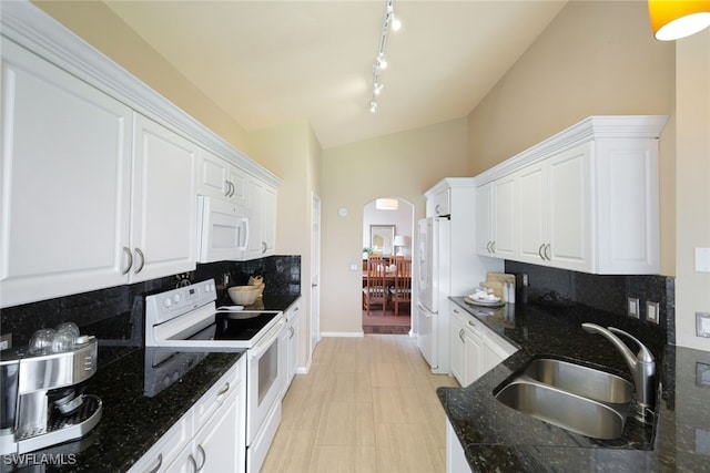 kitchen with sink, white appliances, white cabinetry, dark stone countertops, and decorative backsplash