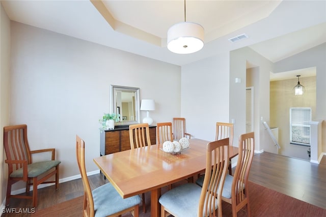 dining space featuring dark hardwood / wood-style floors and a raised ceiling