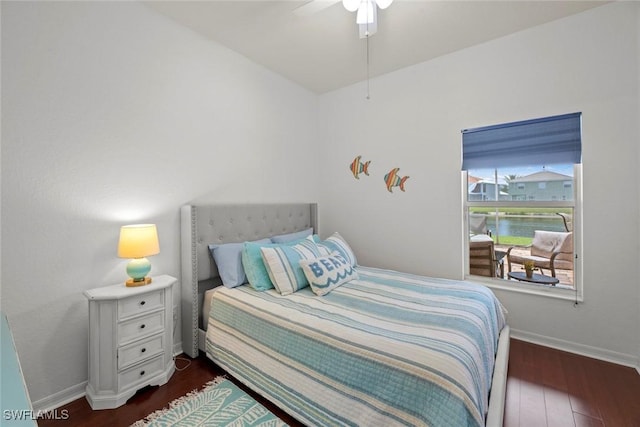 bedroom featuring dark hardwood / wood-style floors, ceiling fan, and a water view