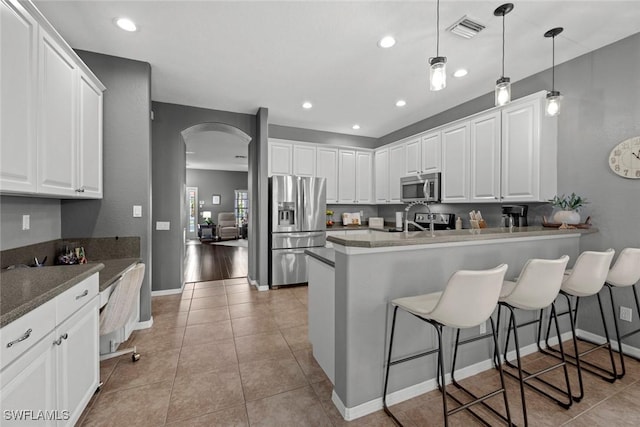 kitchen with stainless steel appliances, white cabinetry, a breakfast bar, and kitchen peninsula