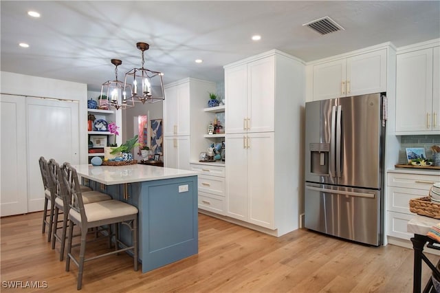 kitchen with white cabinetry, a kitchen breakfast bar, hanging light fixtures, a center island, and stainless steel refrigerator with ice dispenser