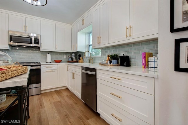 kitchen with stainless steel appliances, sink, white cabinets, and backsplash