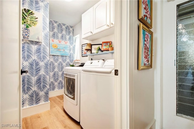 clothes washing area with cabinets, washer and clothes dryer, and light hardwood / wood-style flooring