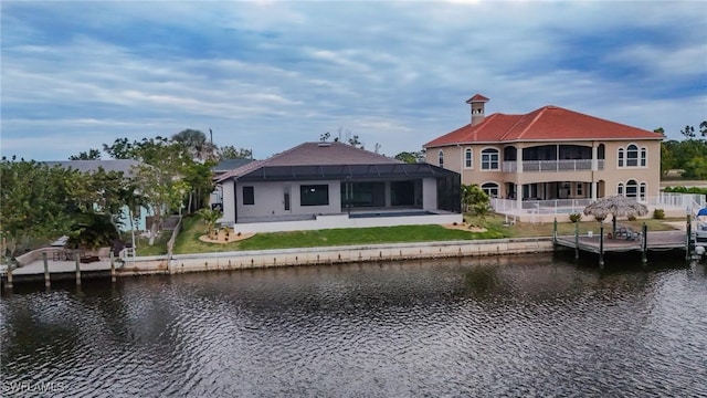 rear view of property featuring a lawn, a patio, glass enclosure, and a water view