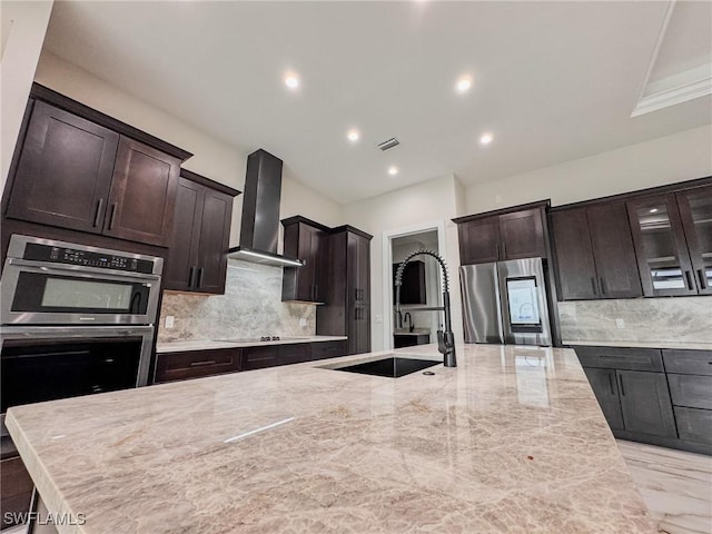 kitchen featuring wall chimney exhaust hood, stainless steel appliances, sink, and backsplash